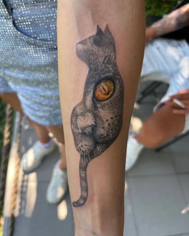 Dotwork forearm tattoo of a cat with a coloured amber eye
